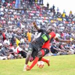 Two players from Kakamega School and St. Mary's School Yala battle for possession during the KSSSA national football final as thousands of spectators watch from the packed stands in Thika.