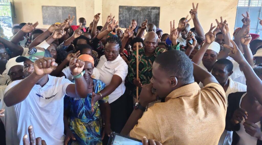 Lugari MP Nabii Nabwera speaking to an excited crowd of women and community members during a women’s empowerment event inside a hall.