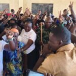 Lugari MP Nabii Nabwera speaking to an excited crowd of women and community members during a women’s empowerment event inside a hall.