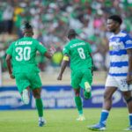 Gor Mahia players in green kits celebrate a goal while an AFC Leopards player in a blue and white kit looks on during a crowded derby match at Nyayo Stadium.