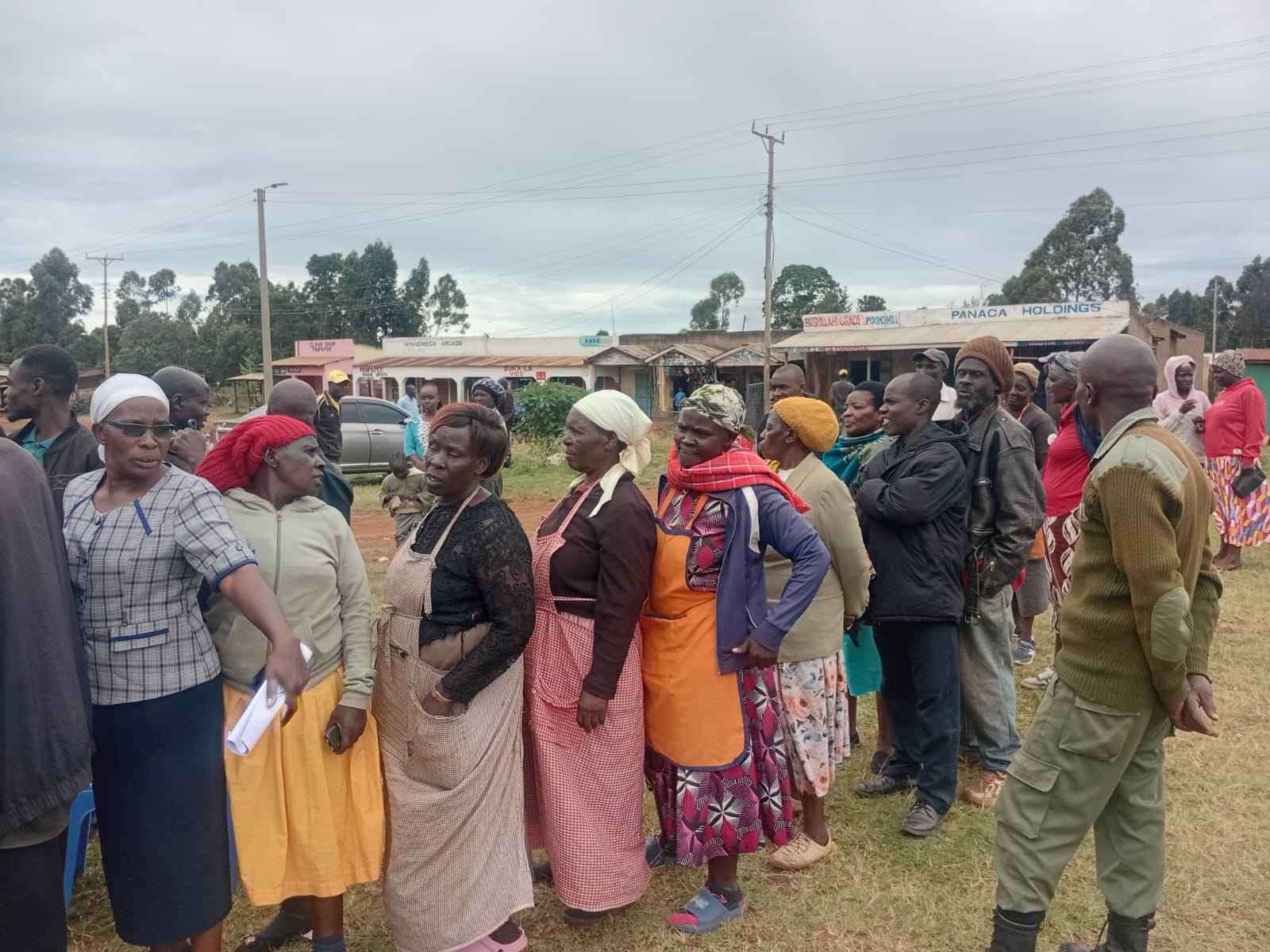 A group of traders, mostly women in aprons and headscarves, stand in a queue outdoors at Panpaper Market in Lugari, waiting to take part in the market leadership election.