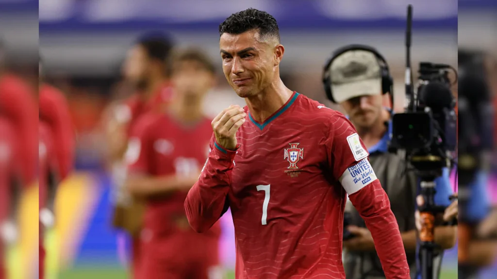 Cristiano Ronaldo of Portugal appears emotional after Portugal's 1-0 loss to Spain in the FIFA World Cup Round of 16, with players and broadcast crew visible in the background.